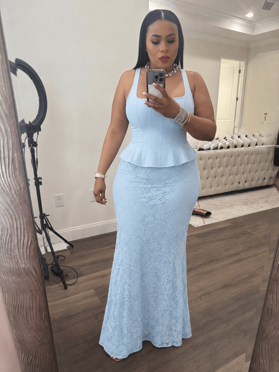 Woman wearing a light blue lace dress taking a mirror selfie.